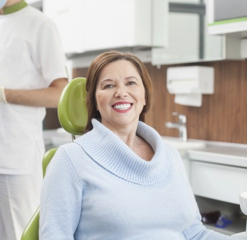 Woman in light blue sweater smiling in dental chair