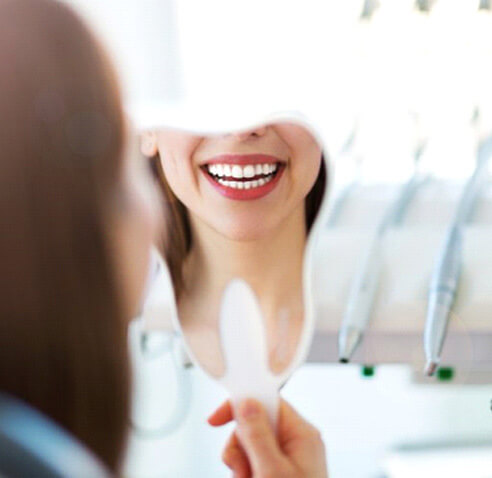 a patient checking her smile after teeth whitening